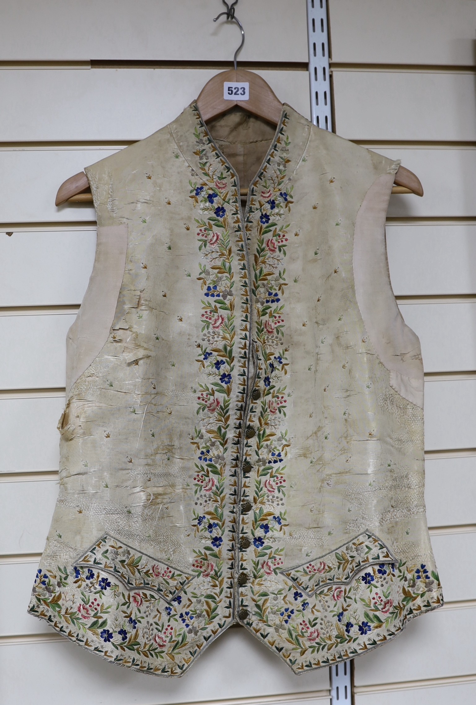 A late 18th early 19th century gentleman’s cream silk waistcoat Embroidered with polychrome silks in a floral design. (The main body of the waistcoat darned and damaged, but the embroidered sections complete).